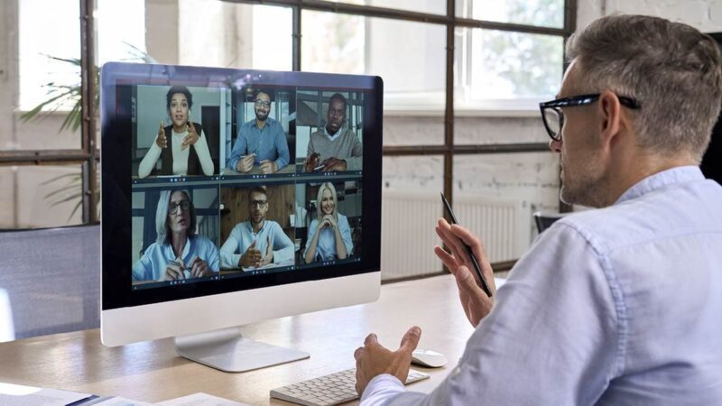 A man sits in front of a computer screen during a virtual meeting.