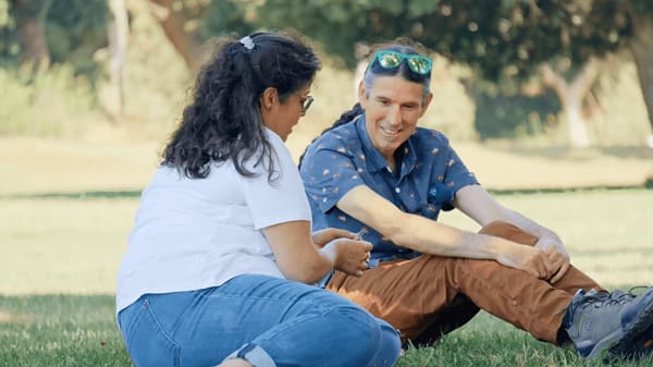 man and woman sitting on ground chatting
