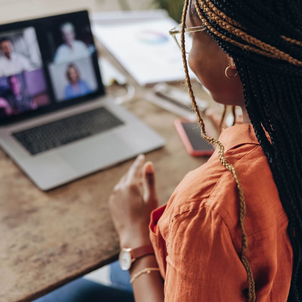 A Black woman talks during a virtual meeting on her laptop.