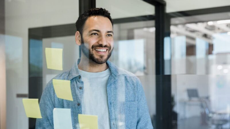 A man looking through a window with sticky notes on it.