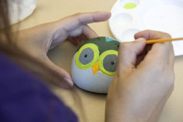 Duarte employee painting an owl on a rock