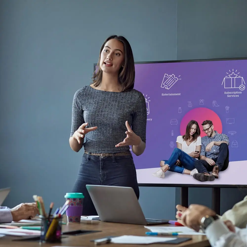 A woman leads a talk while in front a presentation screen.